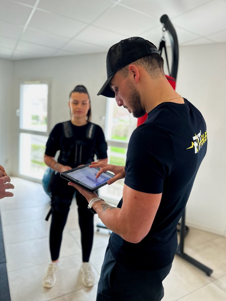 Coach réglant la séance d'une cliente avec la tablette