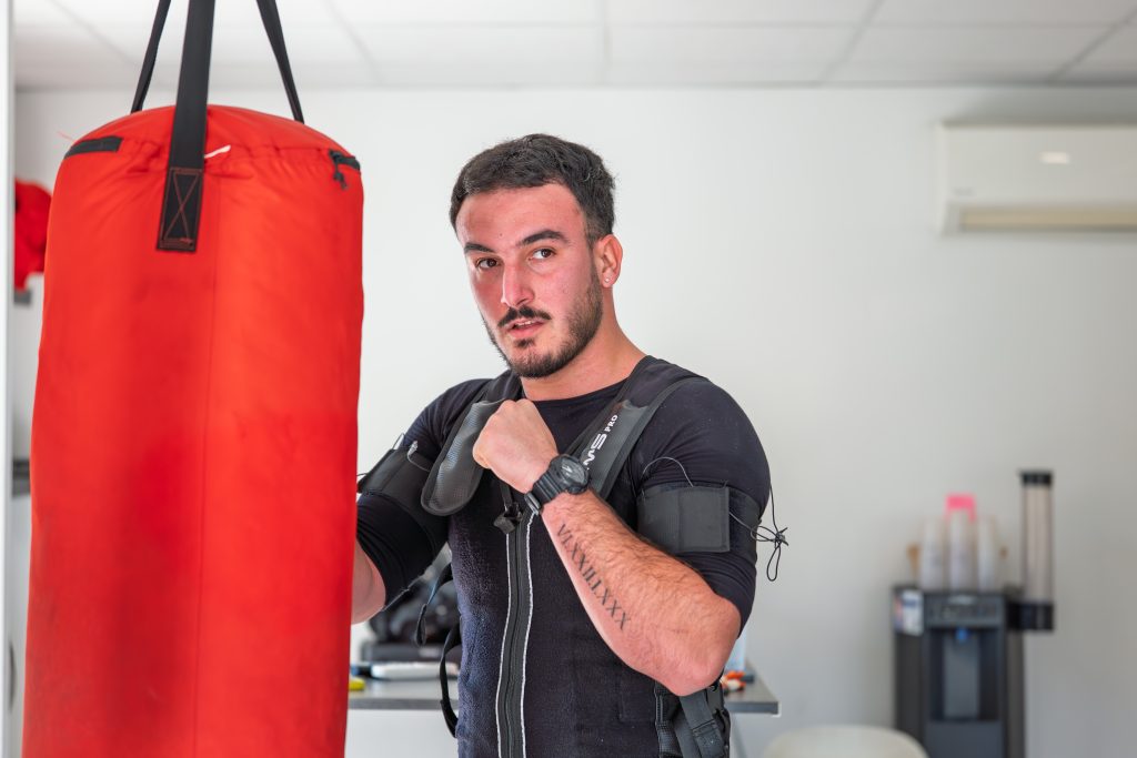 Garde de boxe en combinaison EMS devant le sac rouge