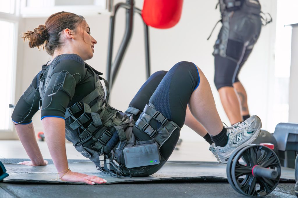Cliente en exercice d'abdominaux au sol en tenue EMS