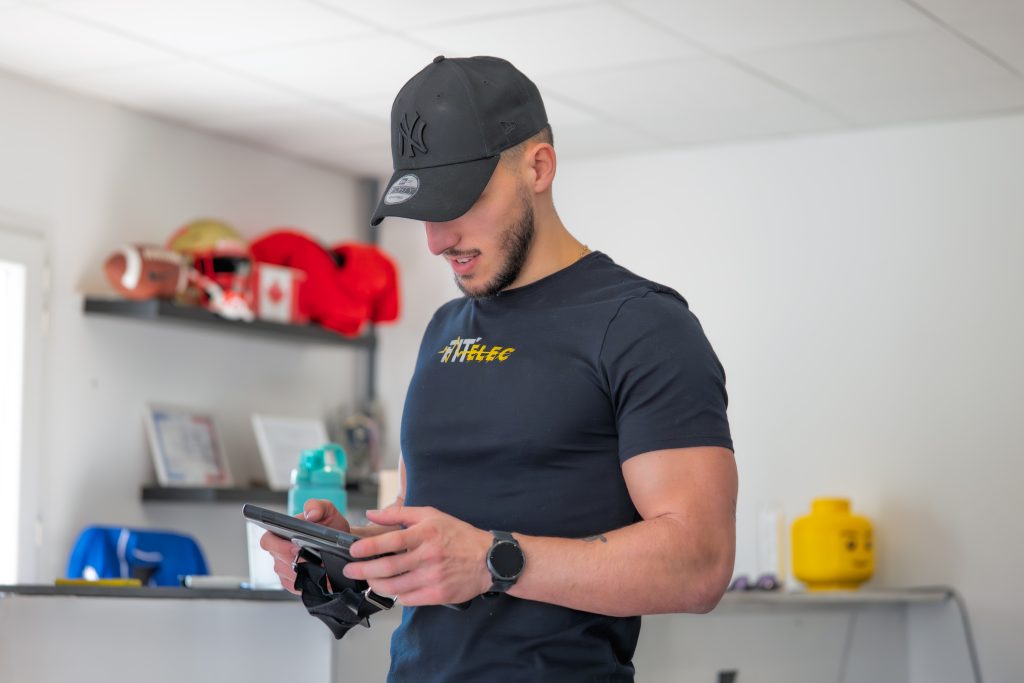 Coach préparant un programme d'électrostimulation sur tablette