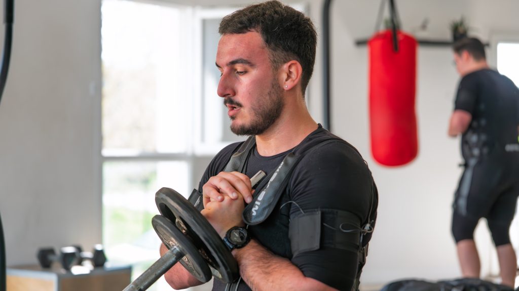 Client concentré sur un exercice de musculation sous électrostimulation