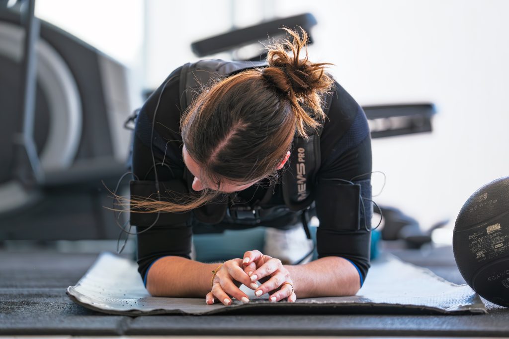 Cliente en gainage sur tapis pendant une séance d'électrostimulation